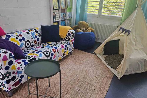 Das Bild zeigt ein Besuchszimmer mit farbigem Sofa, einem Tipi-Zelt, um sich zurückzuziehen, und einem Sitzsatz.