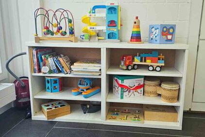 Ein Gestellt mit vielen verschiedenen Spielsachen für Kinder bis 4-jährig (z.B. Musikinstrumente, Stapelklötze, Bücher und mehr).