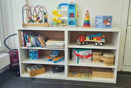 Ein Gestellt mit vielen verschiedenen Spielsachen für Kinder bis 4-jährig (z.B. Musikinstrumente, Stapelklötze, Bücher und mehr).